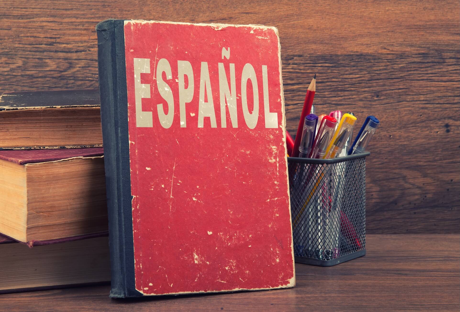 Red Spanish grammar book on a table with wood background.