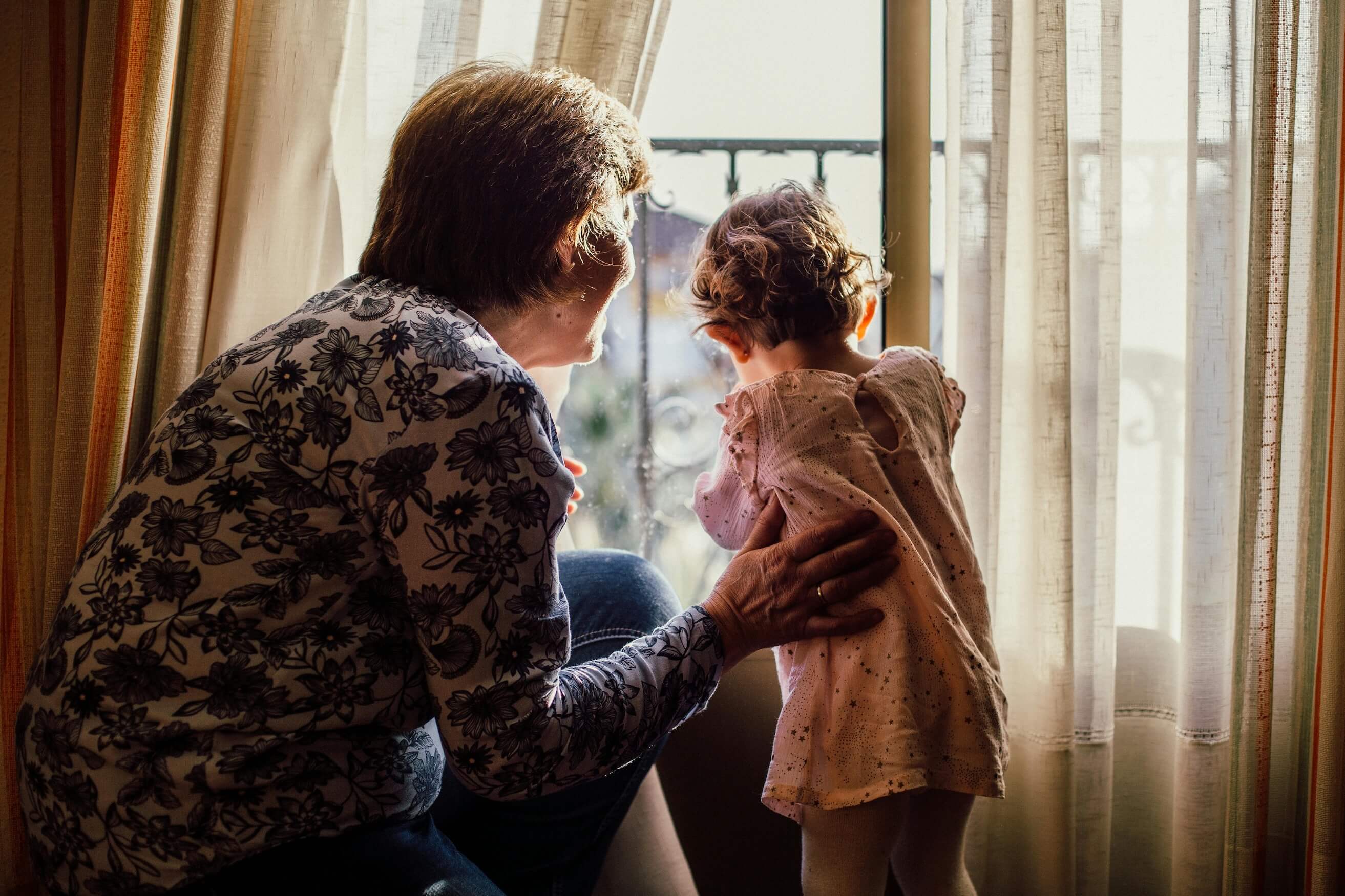 Grandma siting at a window with her grandchild enjoying time together.