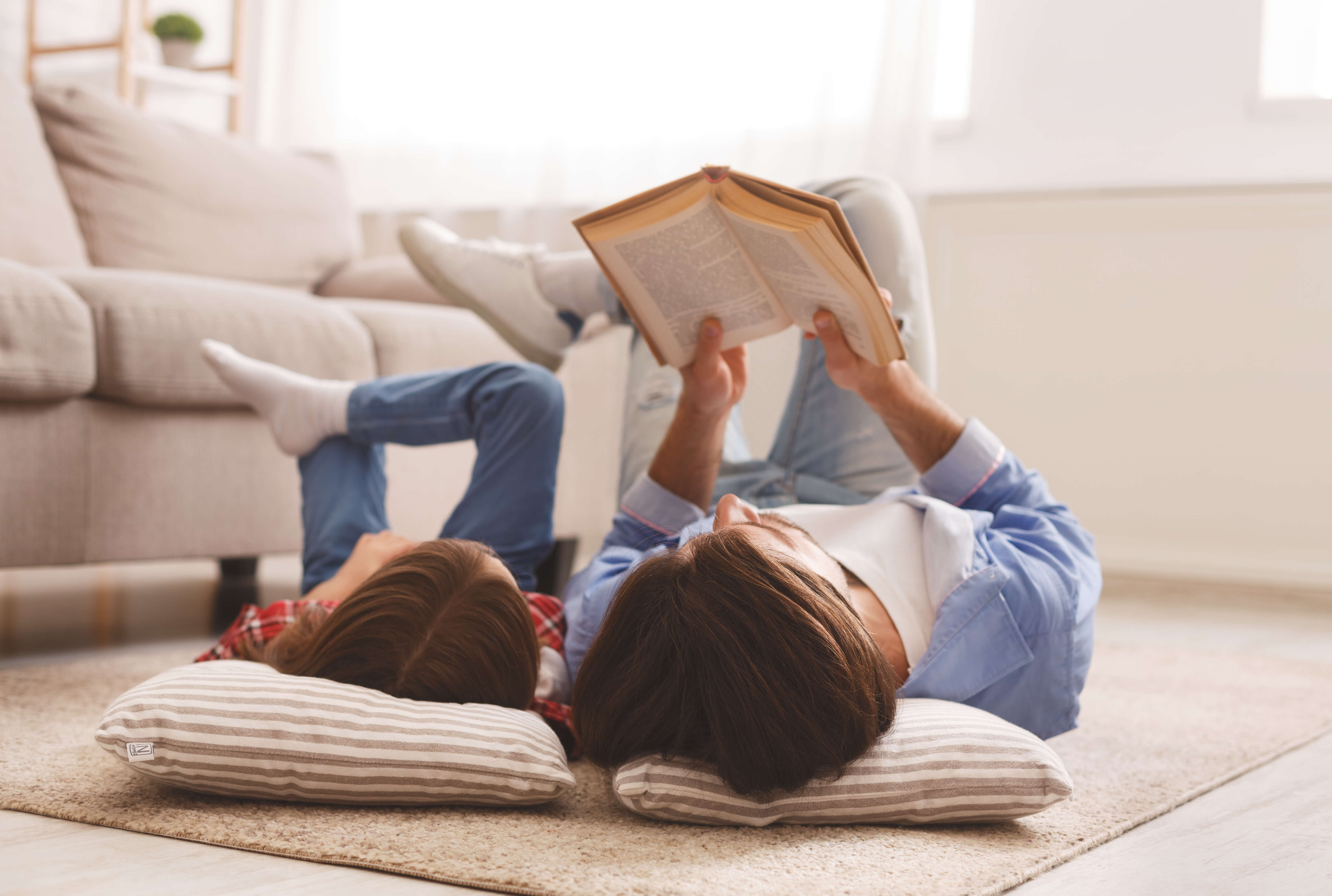 Mother and daughter lying on the floor while reading a book together.