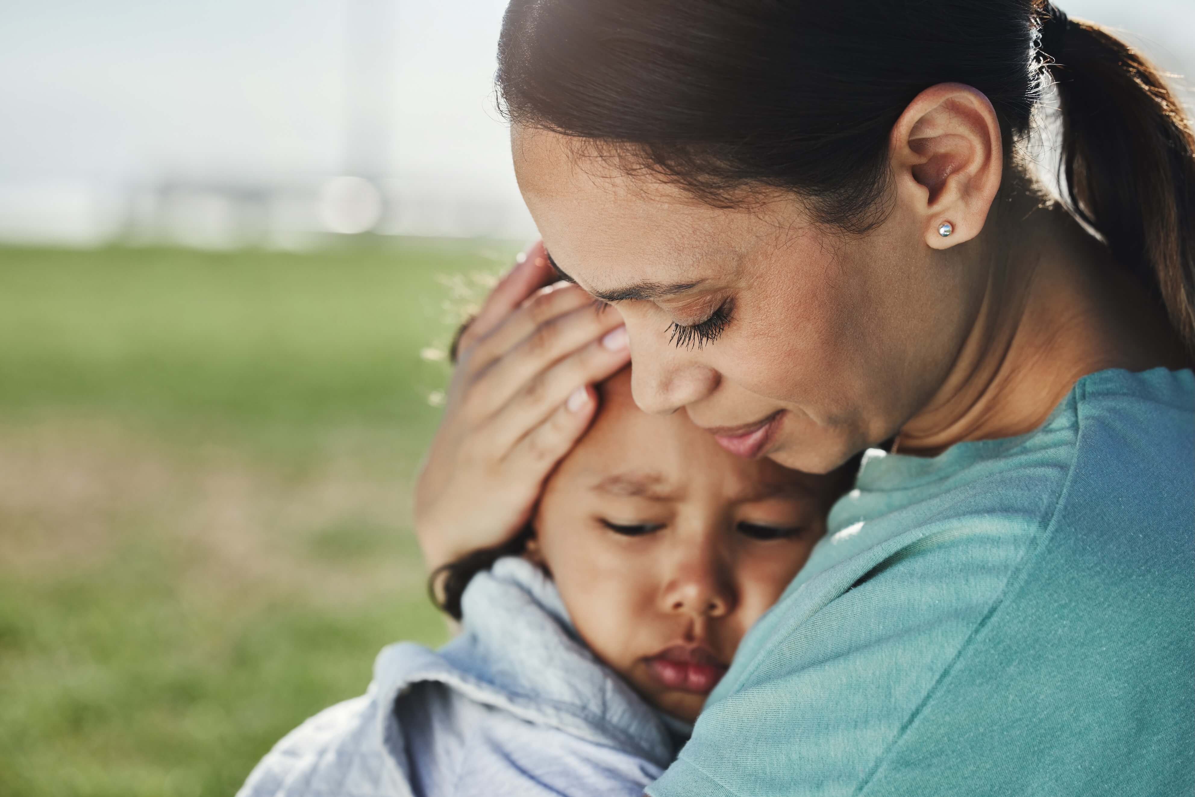 Woman hugging her small child in a park.
